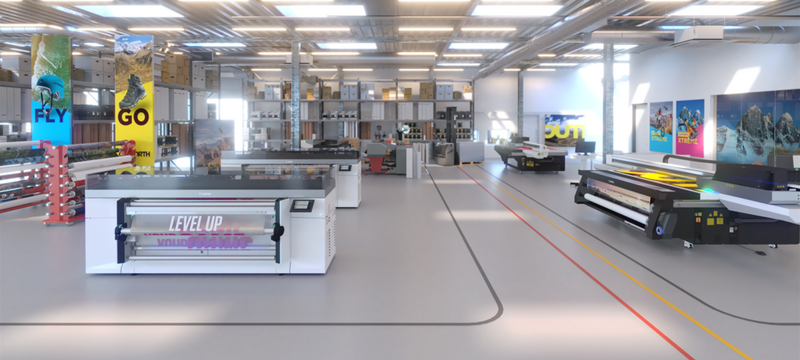 A brightly lit, spacious Las Vegas print shop with various large-format printers, shelves of materials, and colorful posters on the walls. The clean floor is marked with red and yellow lines, and the ceiling has rows of lights and ventilation ducts.