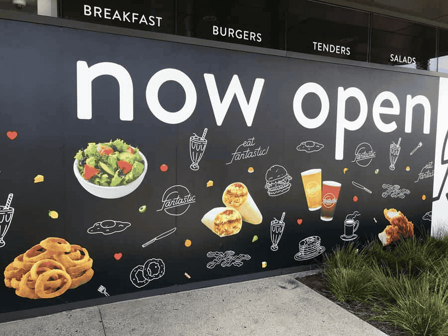 A restaurant sign in Brentwood reads "now open" in large white text on a black background, surrounded by photos of food like burgers and salads. Above are menu categories: breakfast, burgers, tenders, and salads—ideal for business printing needs.