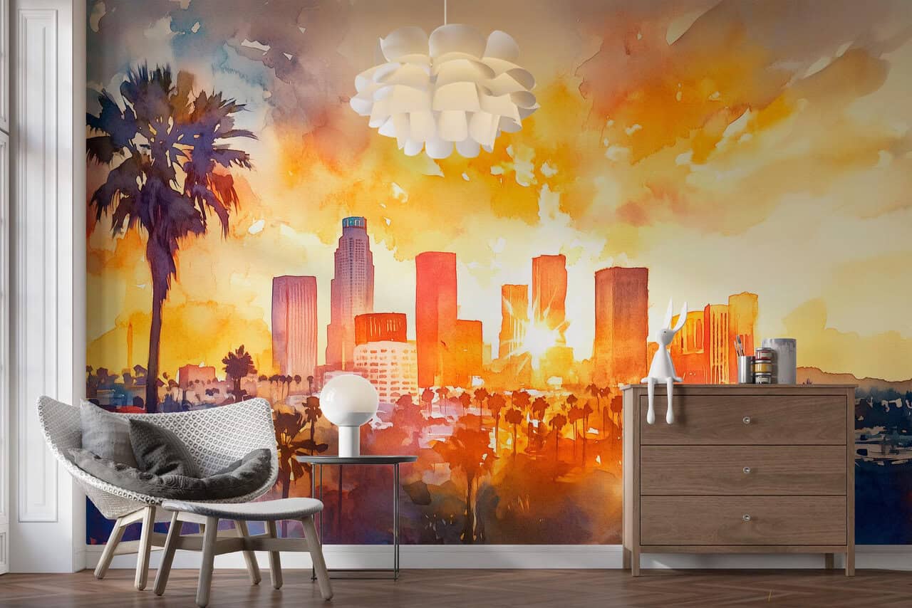 A cozy modern room features a chair, lamp, and dresser in front of vibrant Los Angeles-inspired wall graphics depicting a sunset city skyline with palm trees in warm hues, creating a lively, artistic atmosphere.